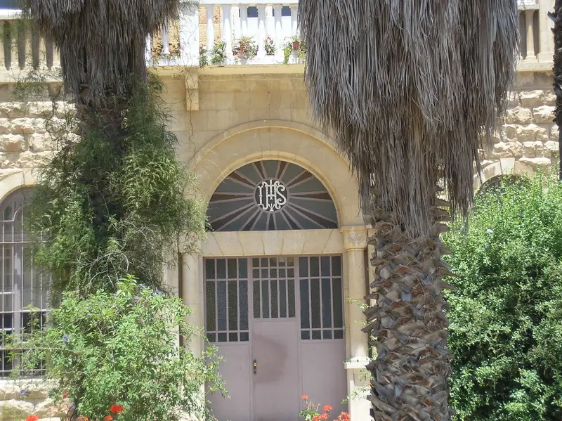 La porta d’ingresso sotto un arco con il monogramma IHS
